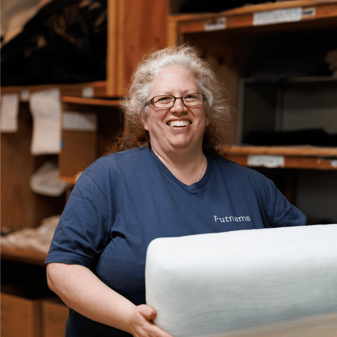 lady smiling at the camera holding a new foam insert for a sofa cushion made from foam with fibre and stockinette